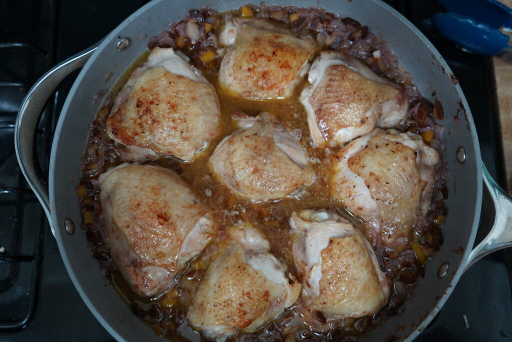 chicken thighs and sauteed vegetables in a pan