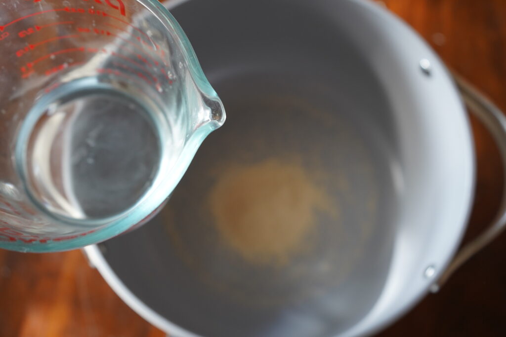 warm water being poured over active yeast in a bowl