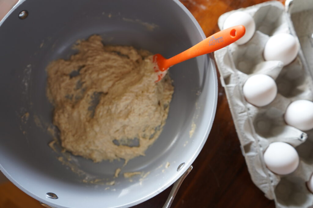 sticky dough for bread in a mixing bowl next to a carton of eggs