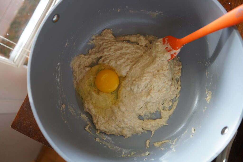 sticky dough with an egg cracked into the mixing bowl