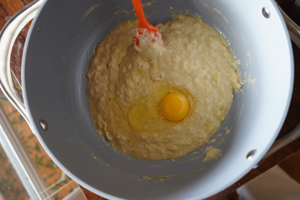 mixing bowl with dough inside and an egg cracked inside