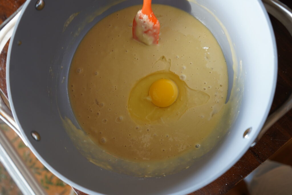 watery dough with an egg on top inside a mixing bowl