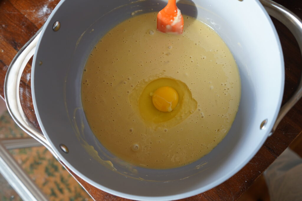 an egg cracked into a mixing bowl of dough