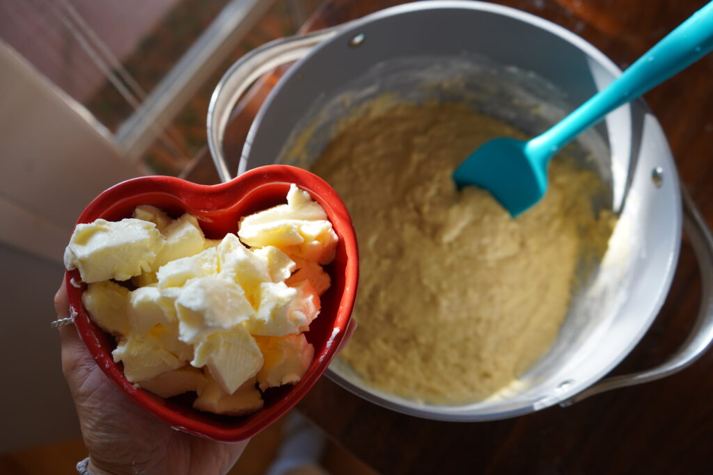 a heart shaped bowl of butter being added to a bowl of dough