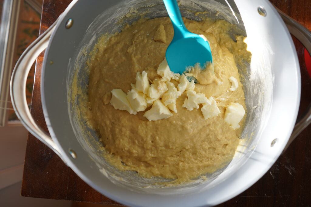 butter being added to a bowl of dough