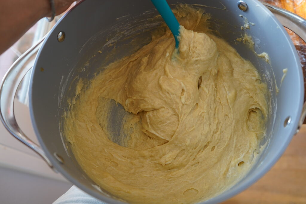 wet and sticky dough n a bowl with a blue spatula mixing it