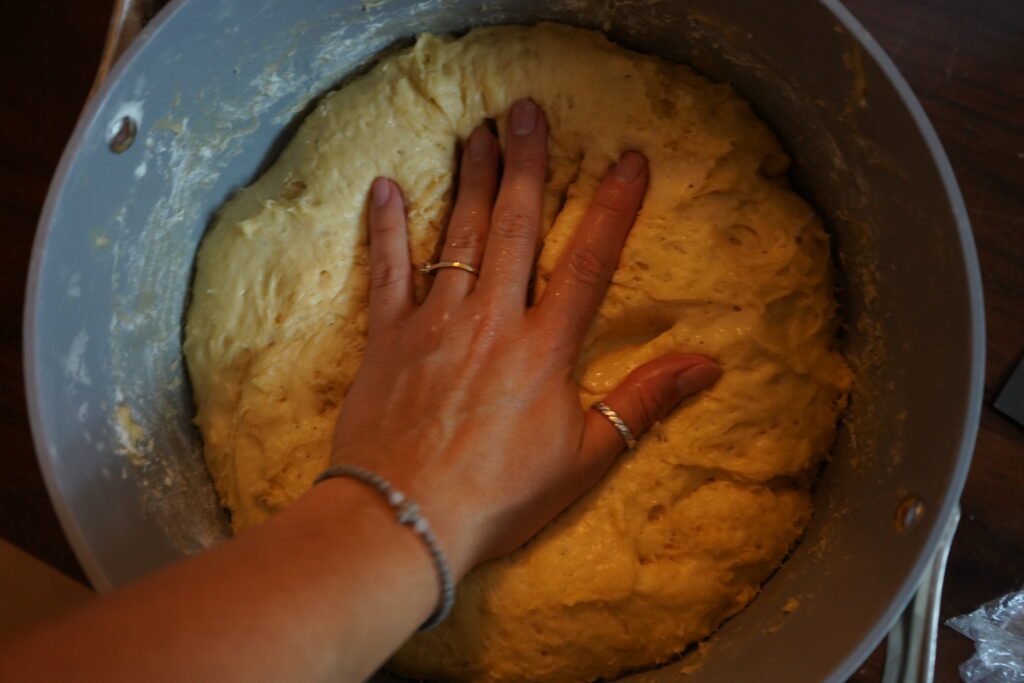 a big ball of dough being deflated by a hand