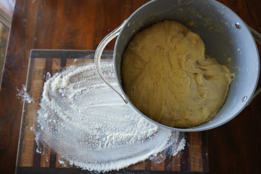 a floured cutting board and a bowl of dough about to be put onto the cutting board