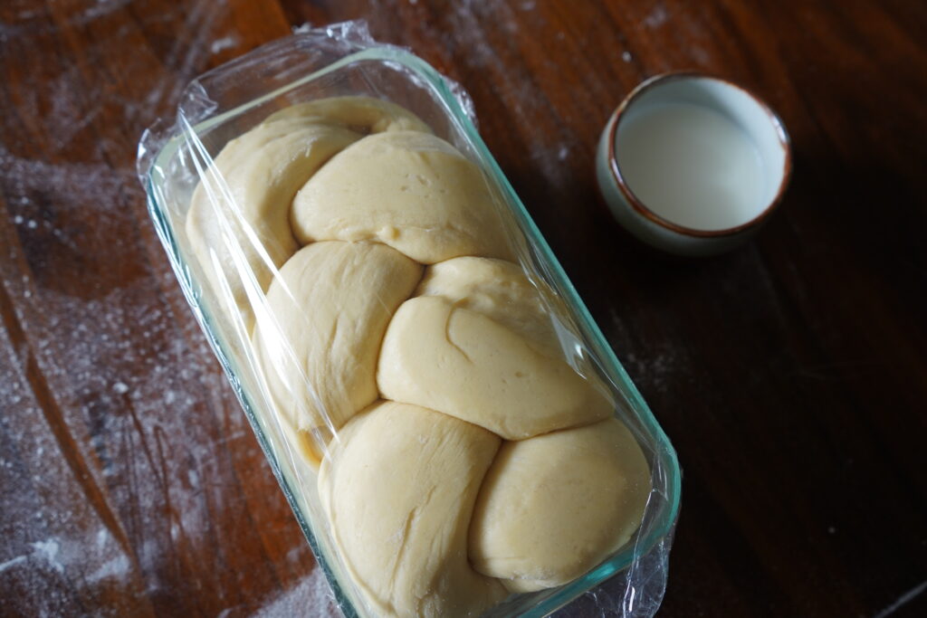 brioche dough covered in plastic wrap