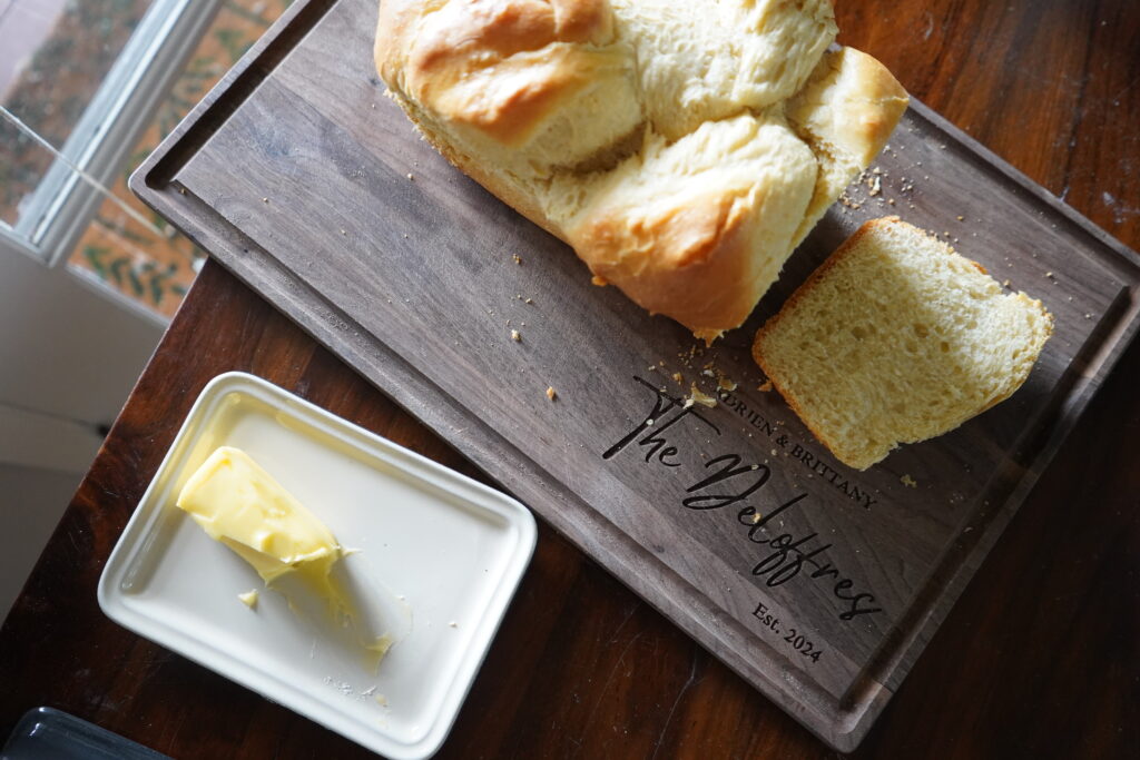 Brioche that is being slice on a cutting board, next to a plate of butter