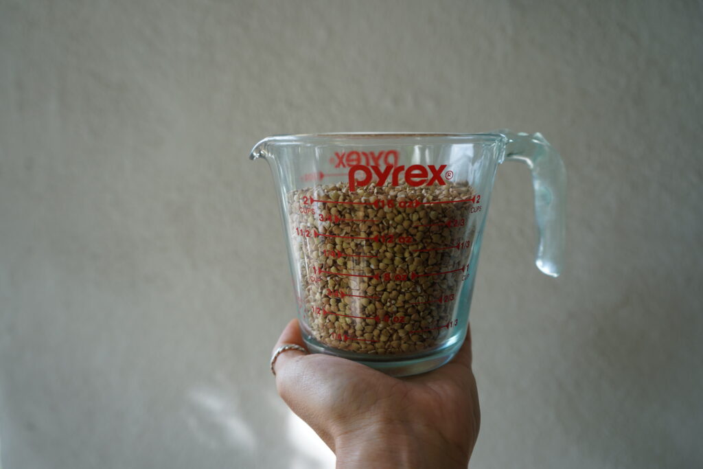 a measuring cup with whole grain buckwheat inside