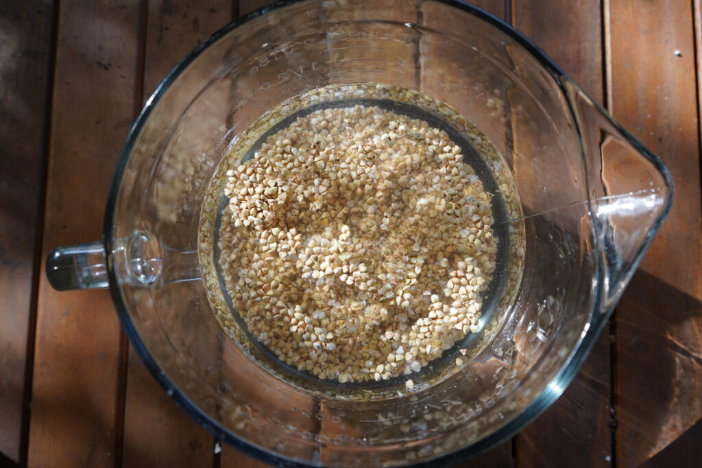 Water submerging buckwheat in a mixing bowl