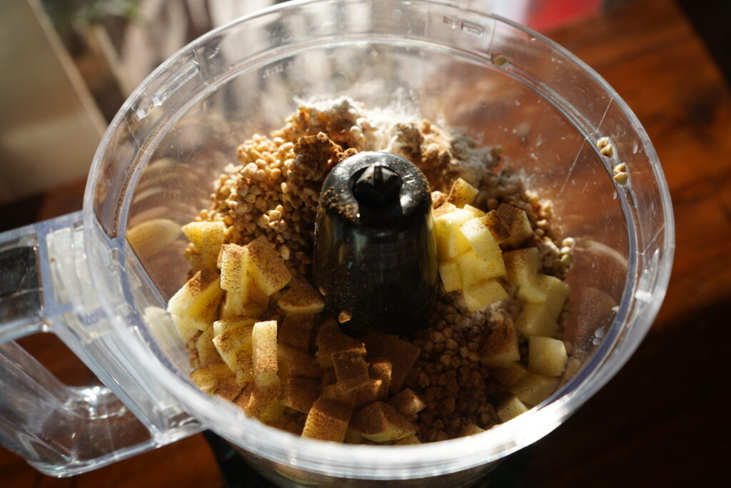 a food processor with buckwheat, apples and cinnamon inside