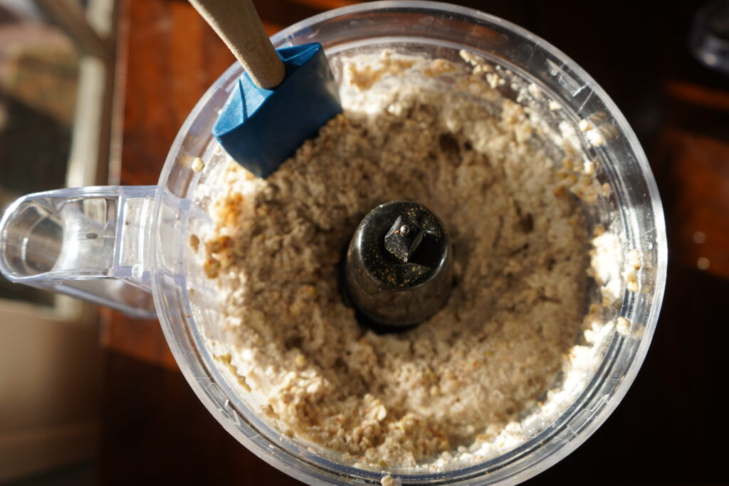 a rubber spatula scraping the side of the food processor