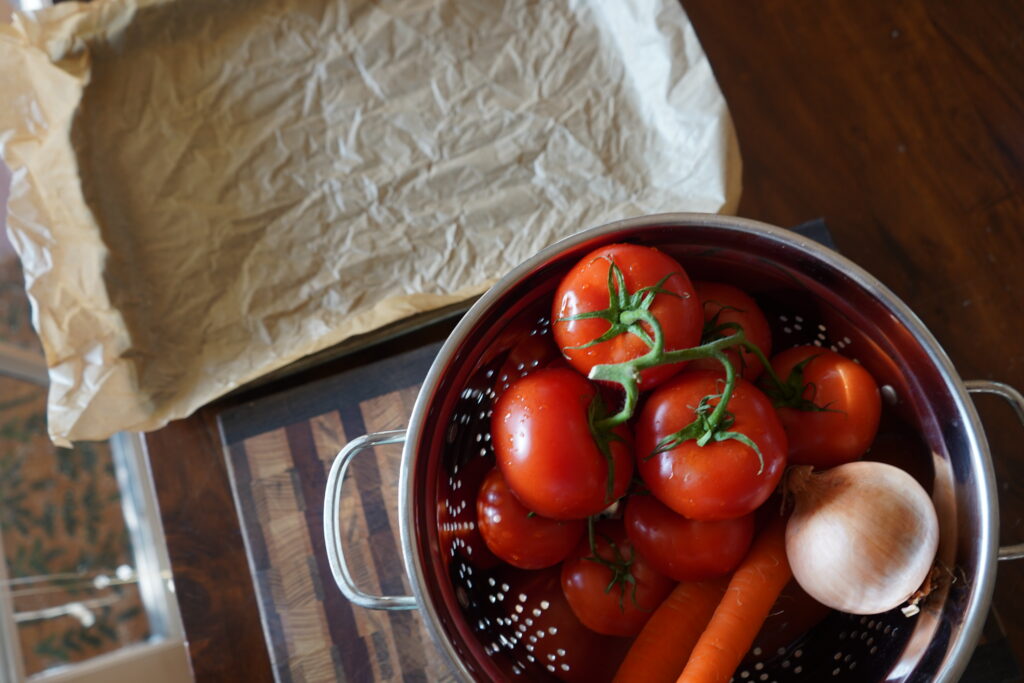 tomatoes, carrots and an onion in a strainer