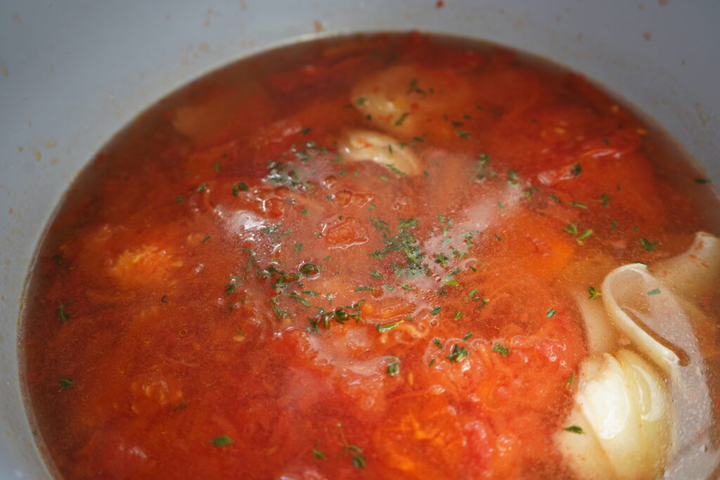 thyme sprinkled on top of a soupy liquid in a pot