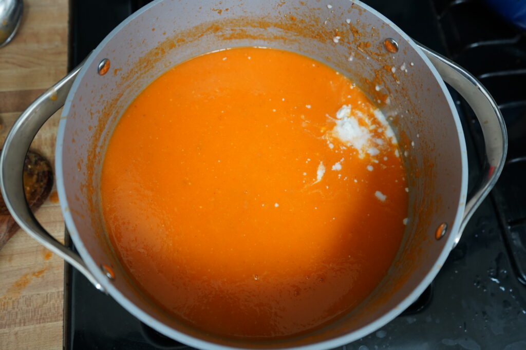 a splash of cream in a pot of orange soup