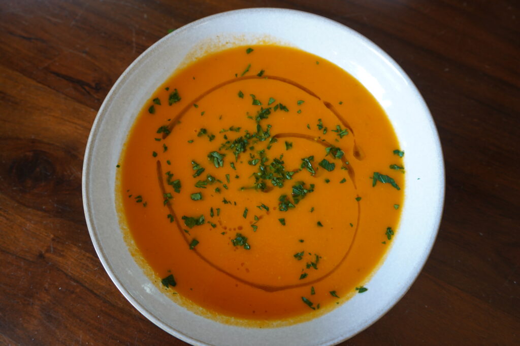 roasted soup made with tomatoes topped with parsley and olive oil