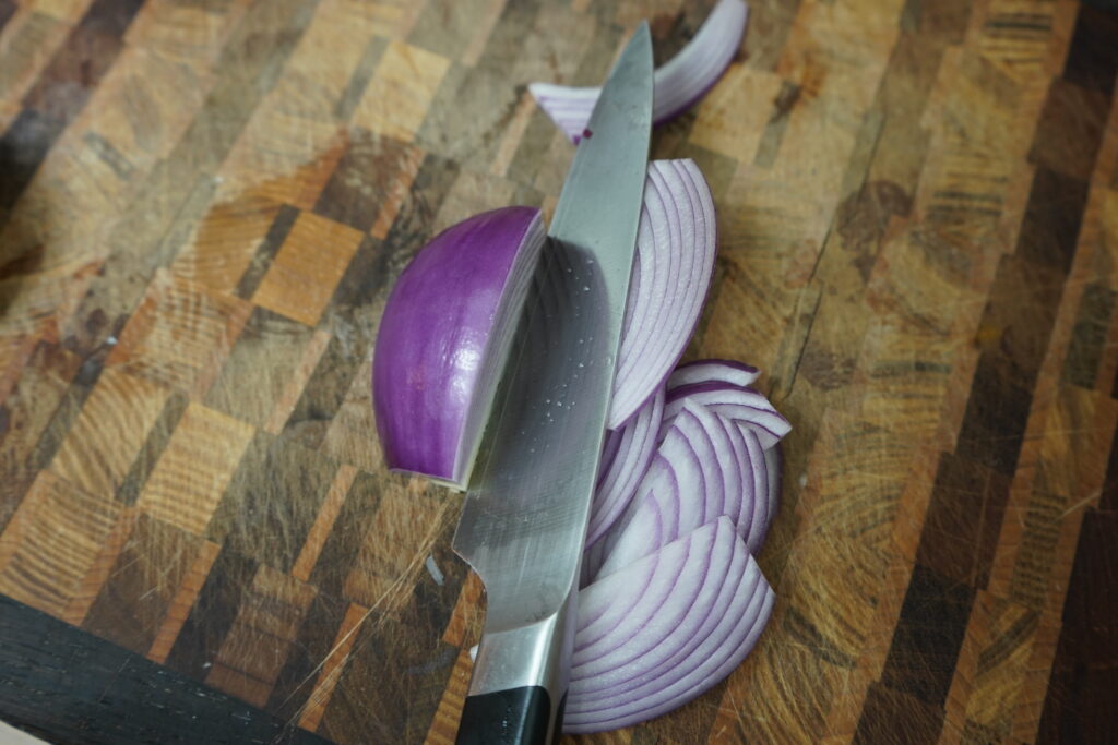 a red onion being sliced on a cutting board