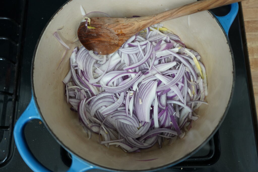 Thinly sliced red onion in a Dutch oven 