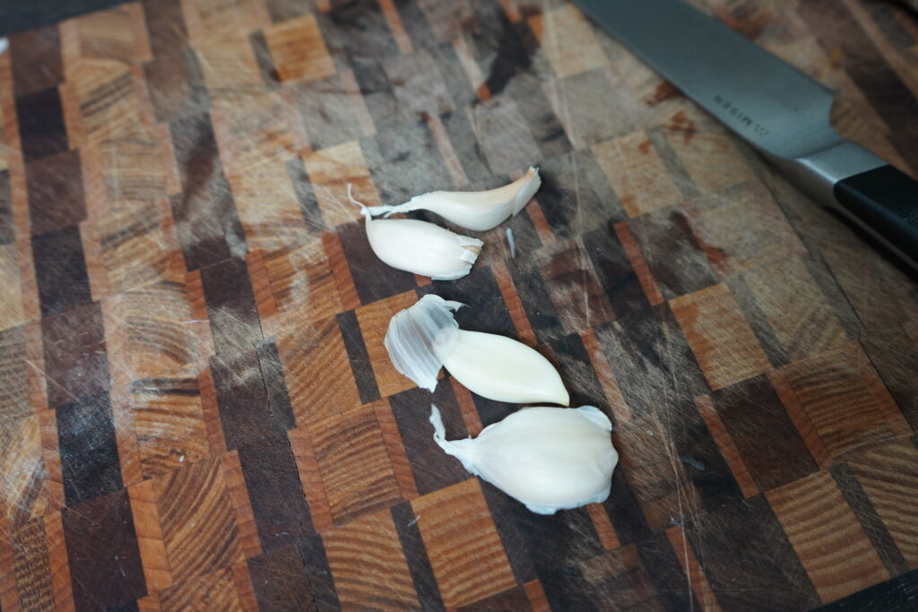 4 garlic cloves on a cutting board