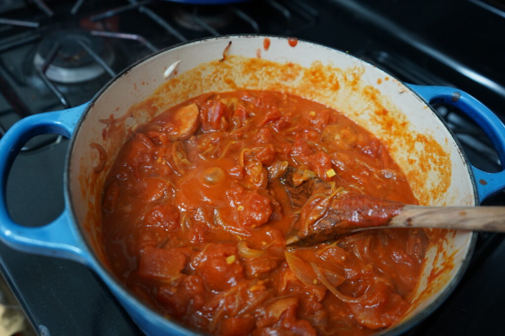 tomato based smoked sausage dish being brought to a boil on the oven