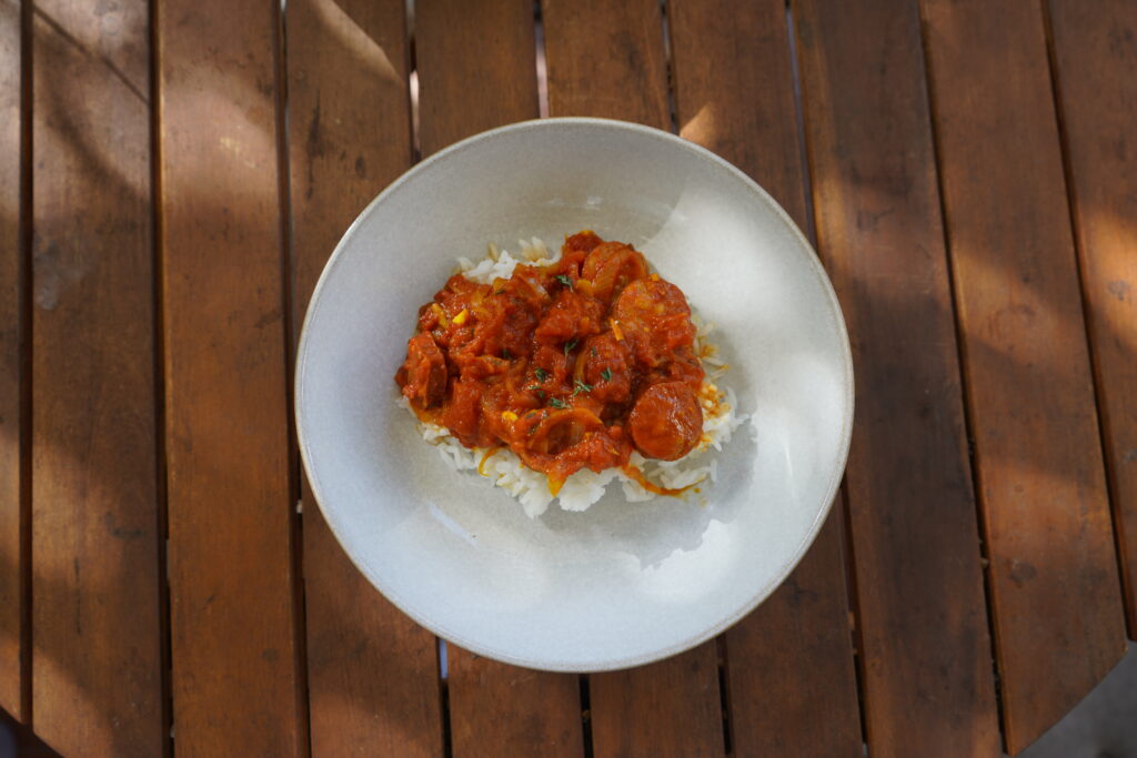 a french dish made with smoked sausages and tomatoes plated on a white dish