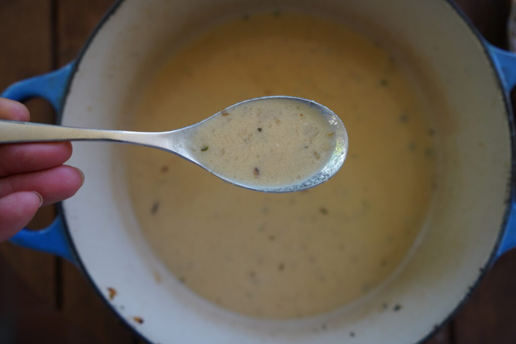 French garlic soup in a Dutch oven being scooped out