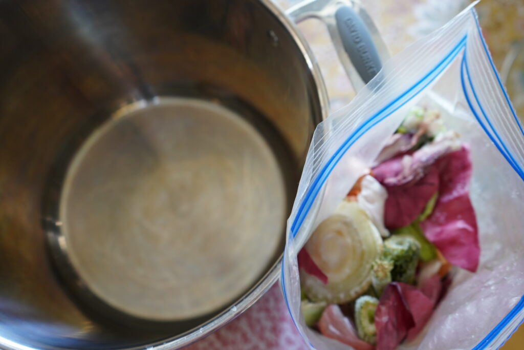 a stainless steel pot next to an open bag of frozen vegetables