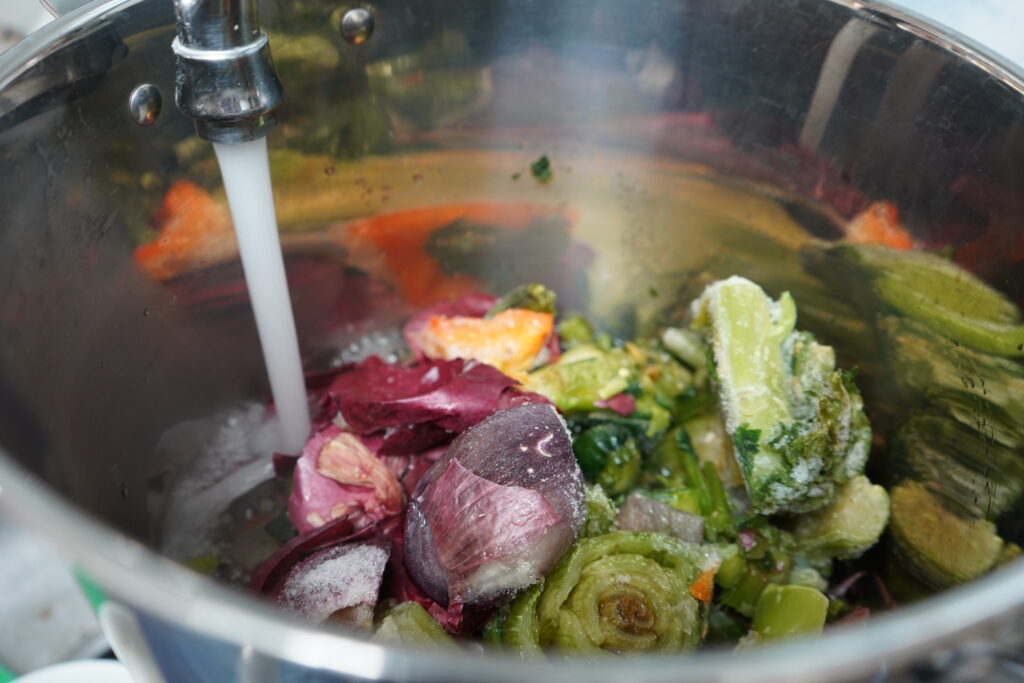 a facet filling up water into the vegetable scrap pot