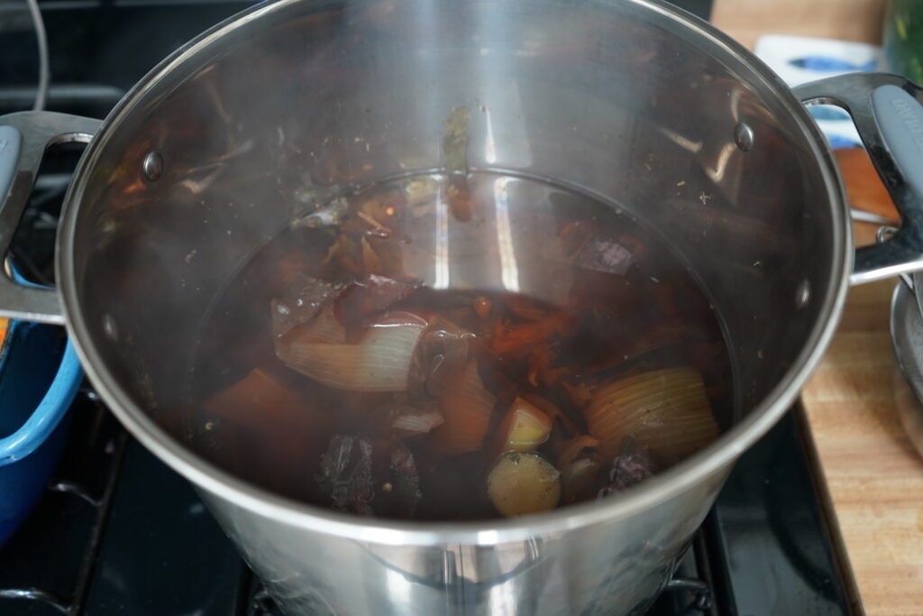 vegeatbles floating in brothy water in a stainless steel pot