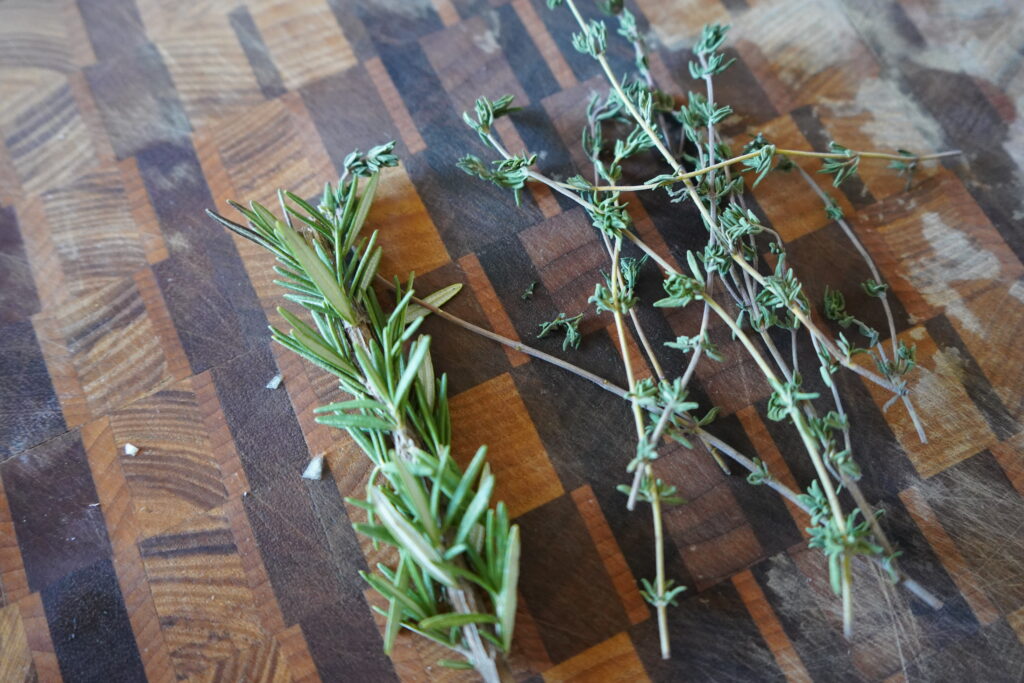 rosemary and thyme on a cutting board