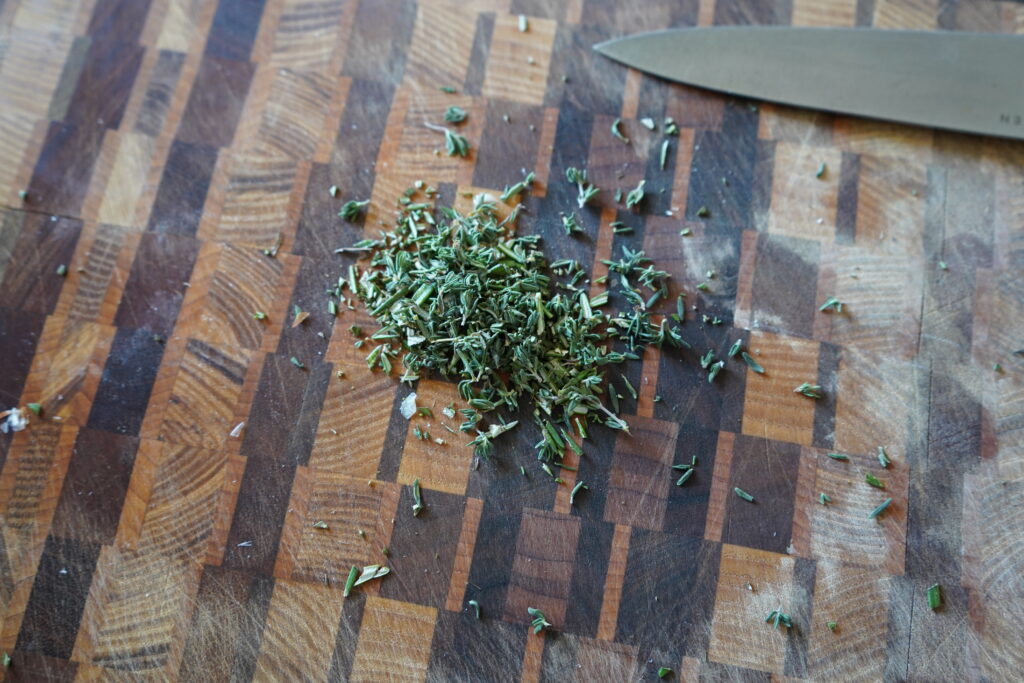 chopped rosemary and thyme on a cutting board