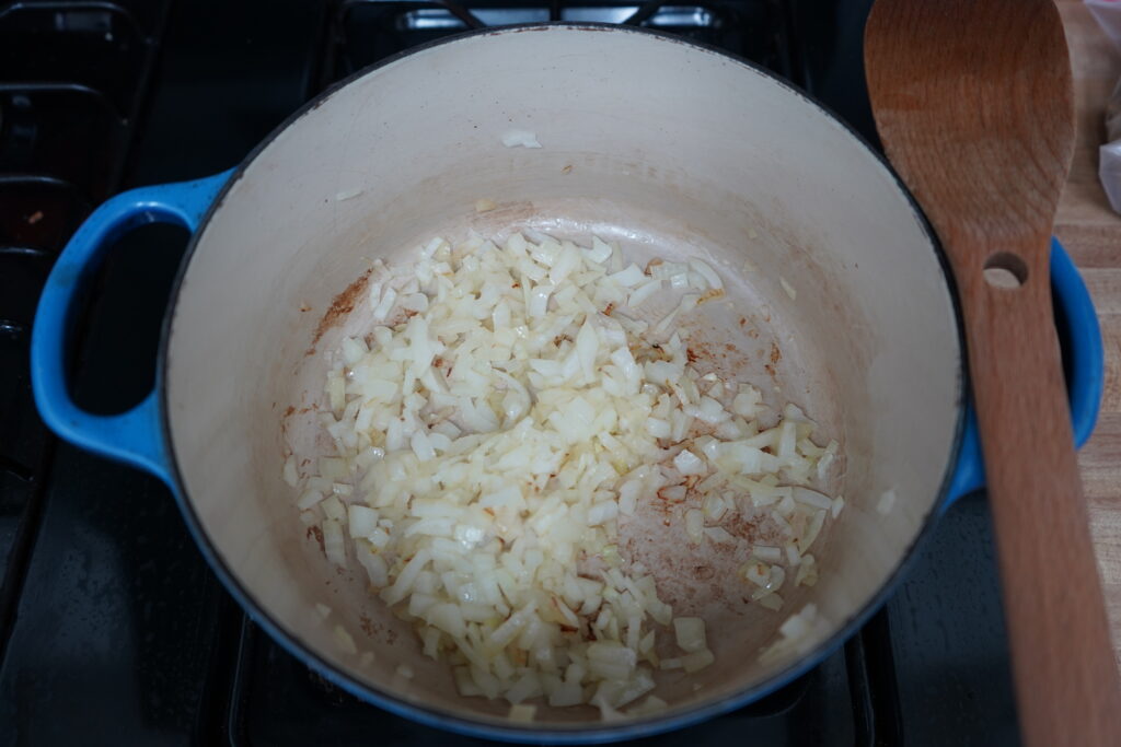 a dutch oven on a stove with sauteed onion inside