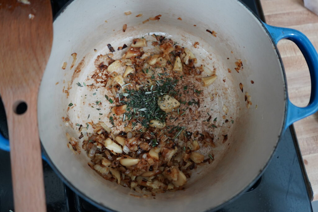 a Dutch oven with sauteed onions and fresh chopped herbs 