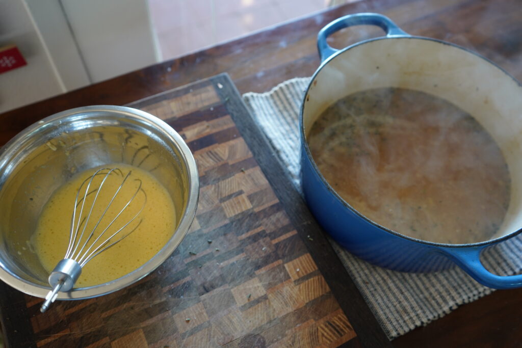 a bowl of egg broth next to w pot of garlic soup