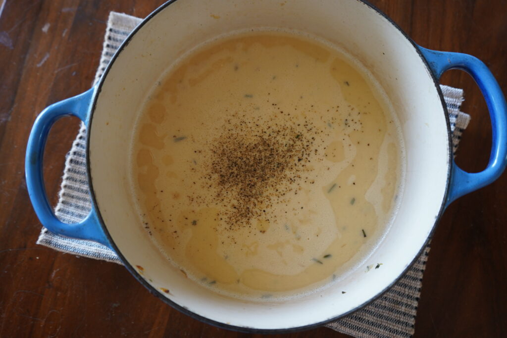 soup in a Dutch oven with fresh garlic on top