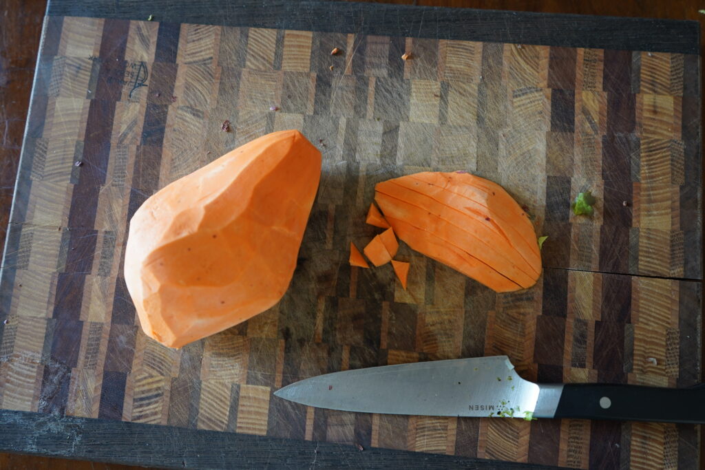 a peeled sweet potato on a cutting board about to be chopped up