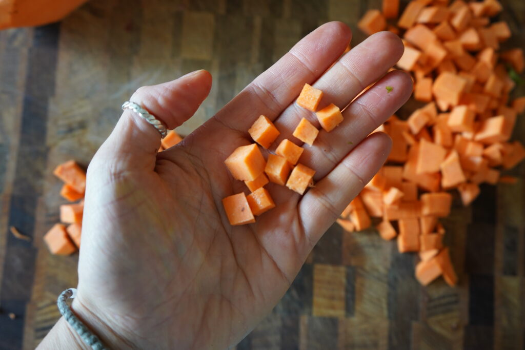 small cubed sweet potato in a hand over a cutting board