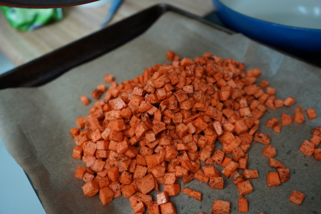 raw sweet potato on a baking tray about to  be cooked