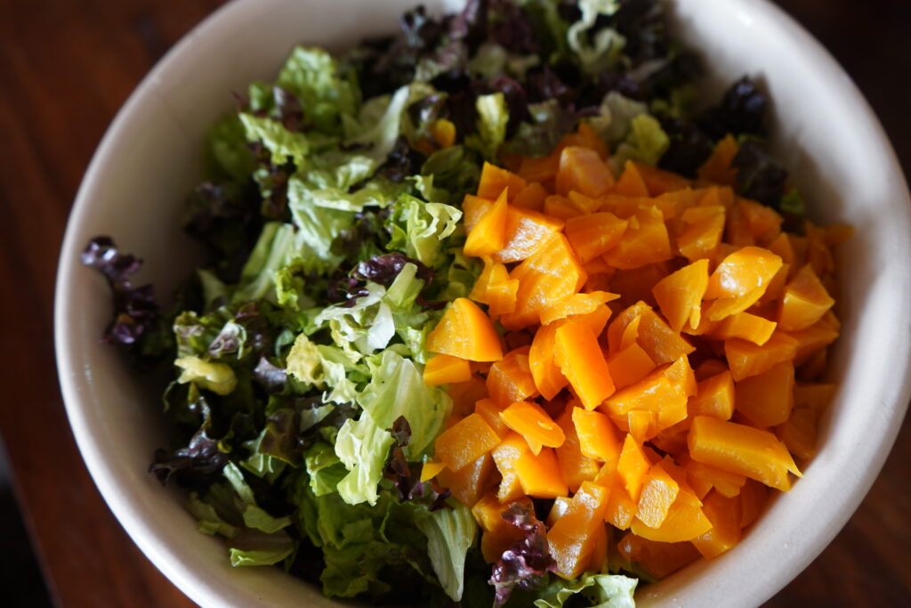 a salad bowl with romaine and golden beets inside