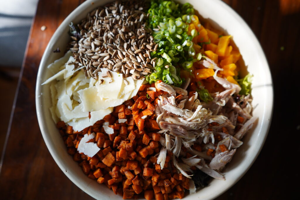 a big salad topped with sunflower seeds, green onions and other toppings