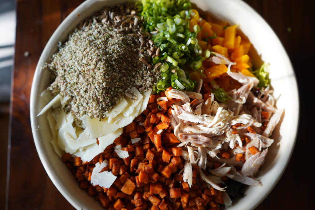 flax seeds and hemps seeds being added to the top of a huge salad