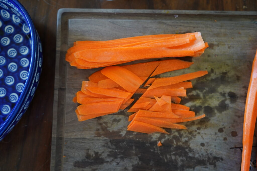 a pile of thinly slice carrots that have been cut in half by a knife