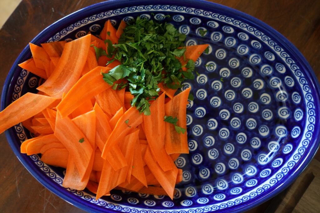 carrots on cilantro in a blue oval salad bowl