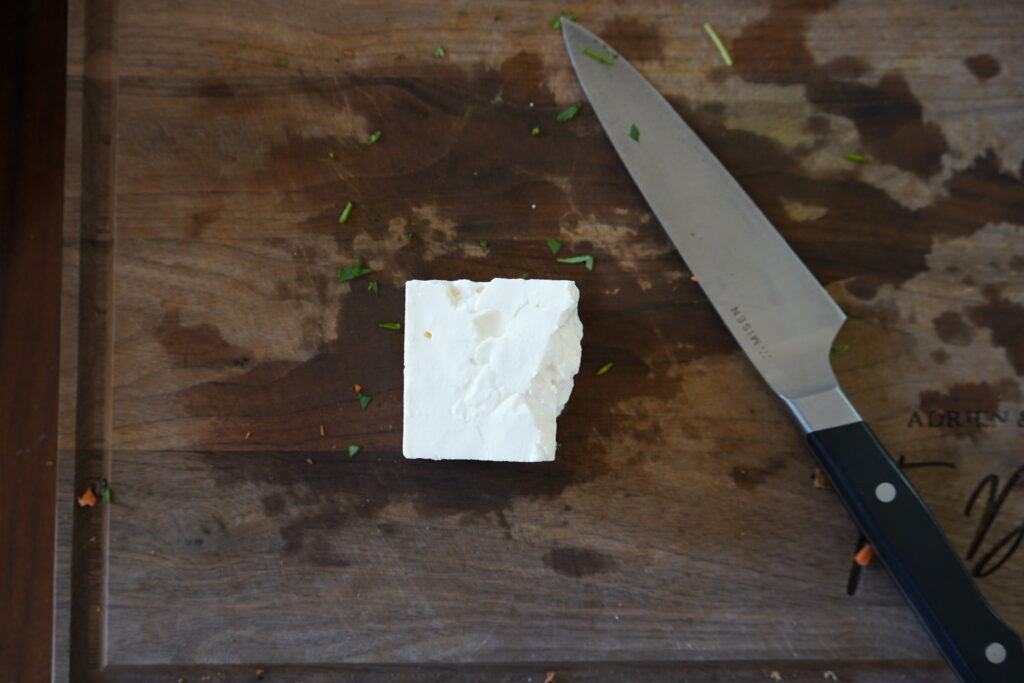 a little block of feta cheese on a cutting board