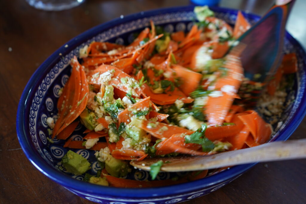 a raw carrot salad with feta being stired