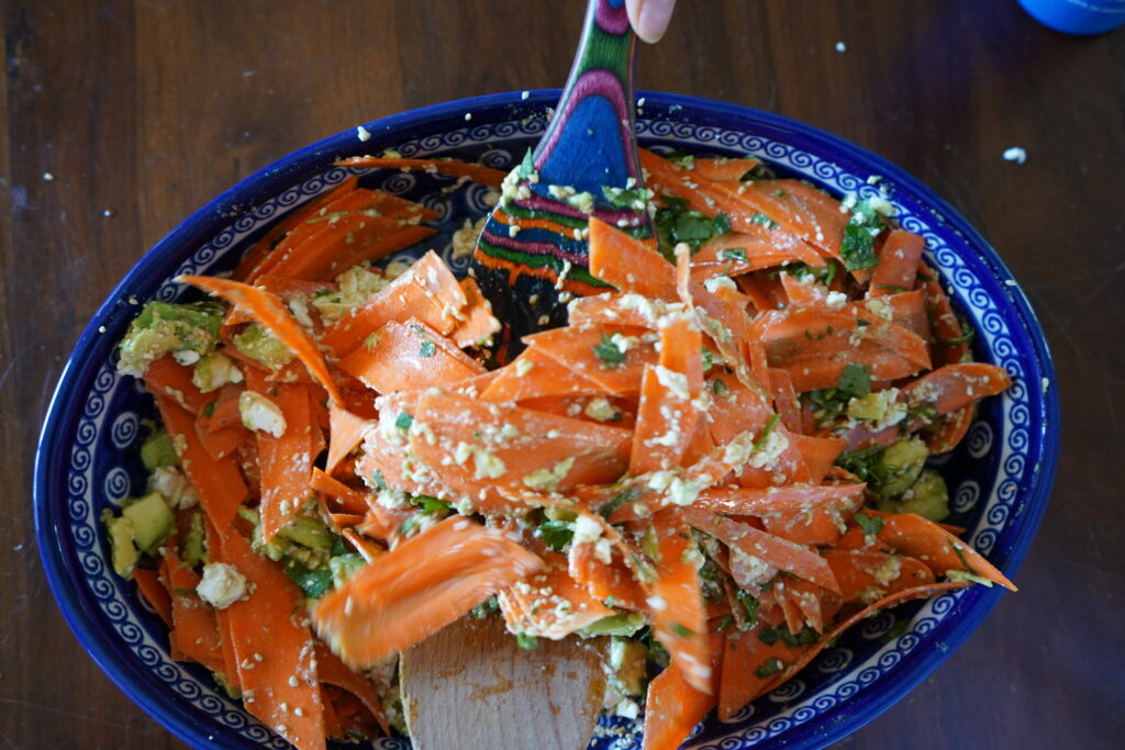 a salad being mixed by two wooden spoons