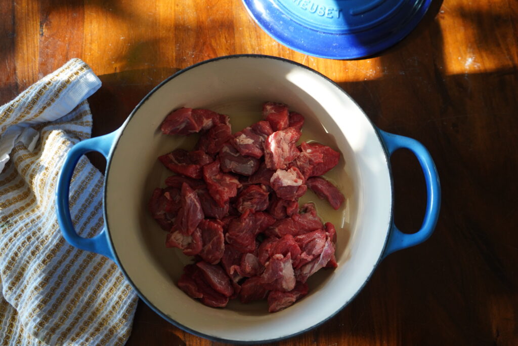 a Dutch oven with beef chunks seering inside