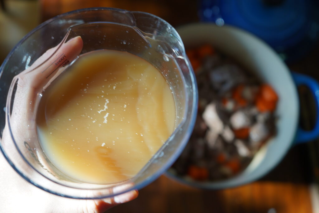 broth being added to a stew pot